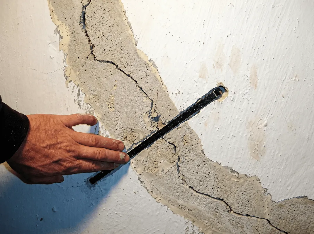 A wall with a large crack is being inspected by a professional in El Paso, TX